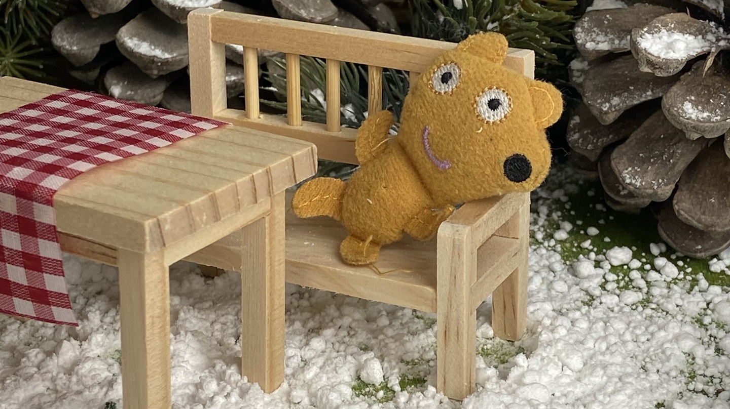 Ein Teddy sitzt auf der Bank vor dem Wichtelhaus.