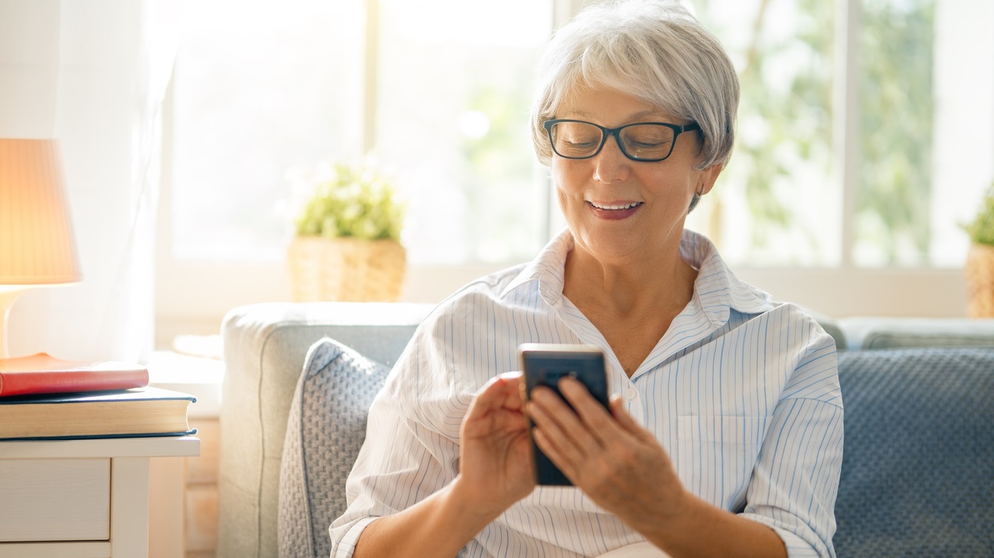 Ältere Dame auf der Couch mit Handy