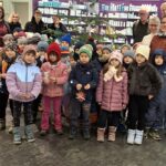 Kindergartenkinder mit Bürgermeister und Bürgermeisterin sowie Erzieherinnen vor einem geschmückten Weihnachtsbaum