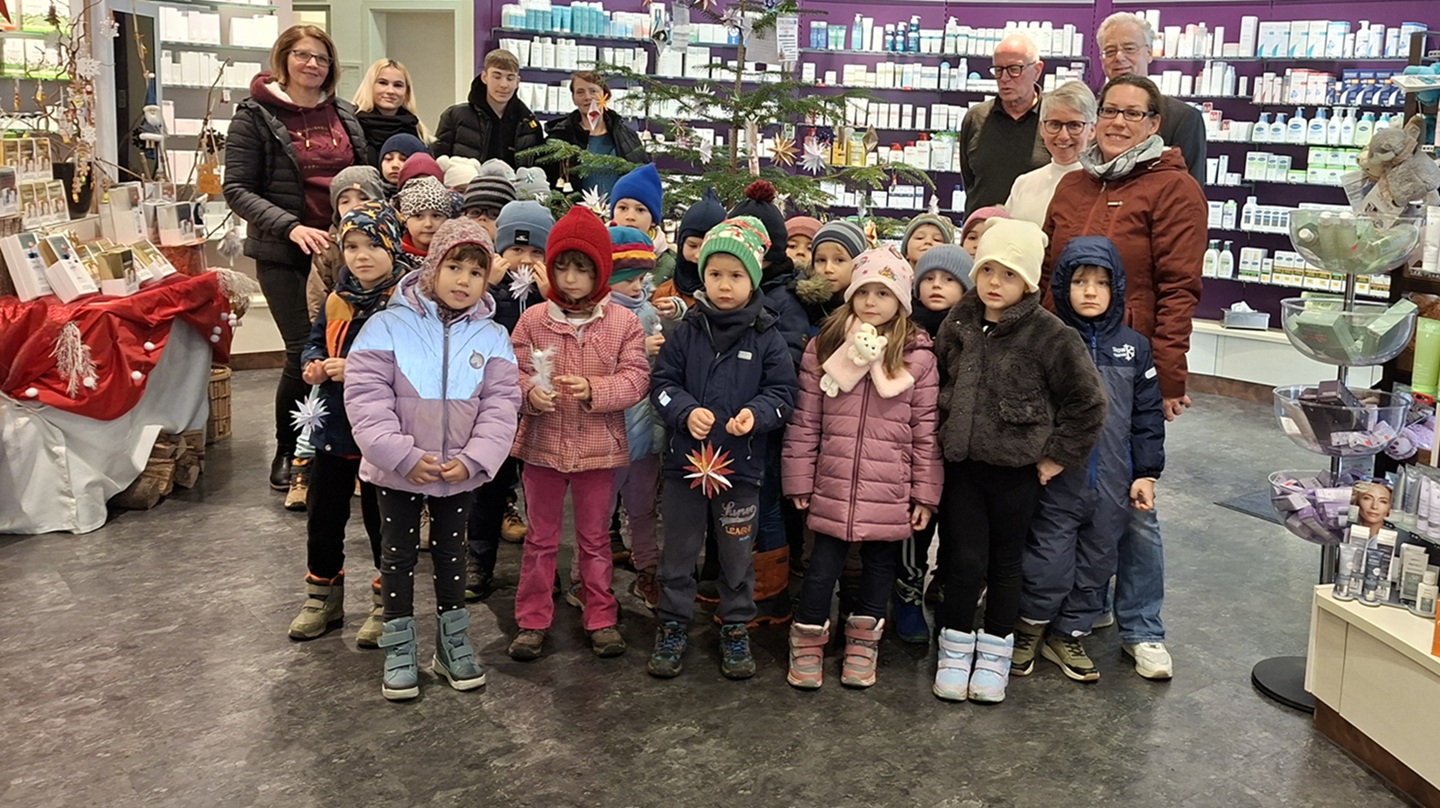 Kindergartenkinder mit Bürgermeister und Bürgermeisterin sowie Erzieherinnen vor einem geschmückten Weihnachtsbaum