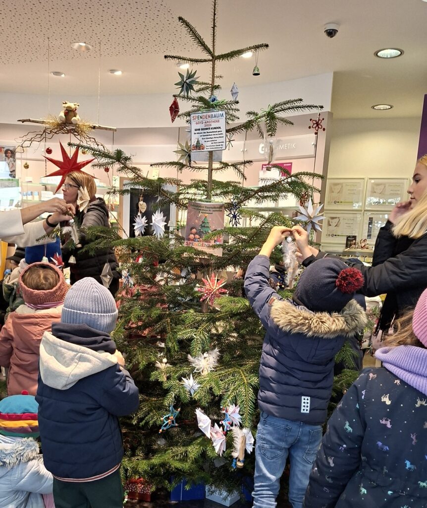 Kindergartenkinder beim Schmücken des Weihnachtsbaums