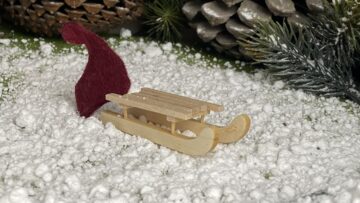 Schneeflocken und Schlitten vor dem Wichtelhaus.