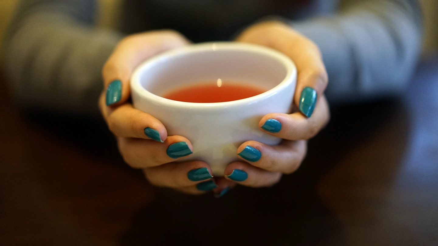 Hände, die eine Teetasse halten