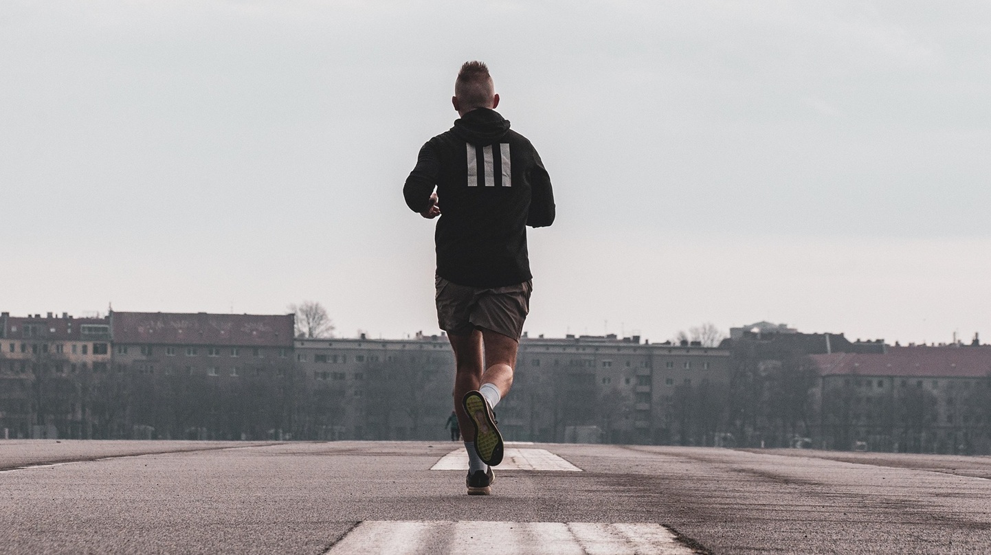 Mann beim Joggen auf einer Teerstraße in einer Stadt.